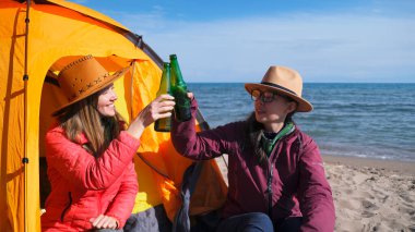 İki kız kardeş deniz kenarındaki bir çadırda otururken bira şişelerini tokuşturur. İki neşeli kadın nehir kenarında dinleniyor. Lezbiyenler alkollü içkinin tadını çıkarıyor 