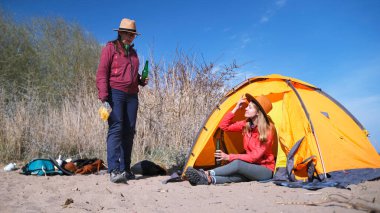 İki kız arkadaş çadırın yanındaki sahilde dinleniyor. Kadınlar dışarıda abur cubur yer ve bira içerler. Kadın alkolizmi işte. Turizm, yürüyüş ve maceralar. Tatil ve eğlence