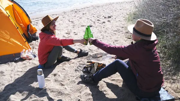 İki kadın sahilde oturmuş yeşil bira şişelerini tıkırdatıyor. Deniz kenarında uzun zamandır beklenen bir tatil. Gezginler çadırı olan yabaniler gibi dinleniyor. Öğrenciler hafta sonlarını aktif olarak geçirirler