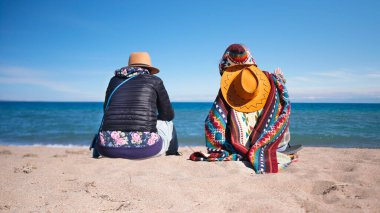 Turistler doğadaki koşuşturma ve koşuşturmaya ara verdiler. Doğayla birlik. Romantik bir randevu. İki kişi sahilde oturuyor. Kumsal sakin ve huzurlu..