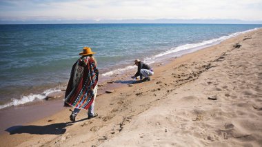Güneşli bir günde iki kız kardeş plaj boyunca yürüyorlar. Kadın kovboy şapkası ve panço giyiyor. Turizm, macera ve özgürlük. Etkin eğlence.
