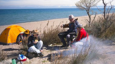 Bir grup iyi arkadaş sahilde eğlenmek için toplandı. Ailenin babası telli bir müzik aletini çıkardı. Bir grup insan kamp ateşinin etrafında oturuyor.