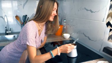 Genç bir güzellik, sıcak bir mutfaktaki ocağın üzerinde bir Türk 'ün içinde kahve demlenişini izler. Bir kadın mutfakta kahve yaparken gülümsüyor. Pembe bir elbise ve bilezik takıyor.