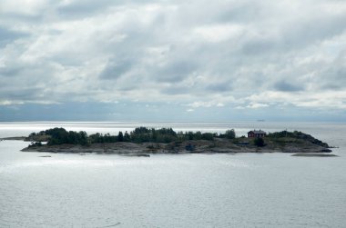 Helsinki 'nin (Finlandiya) dışındaki bulutlu gökyüzünün altındaki küçük konut adasının sabah manzarası).