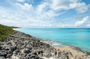 Yarım Ay Geçidi 'nde (Bahamalar) keskin aşınmış bir sahil manzarası ve kumlu bir plaj manzarası vardır.).