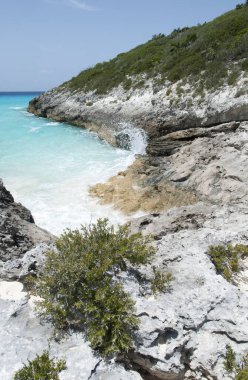 Half Moon Cay 'de kayalık sarp kıyı şeridinin manzarası ve dalgalar ıssız bir adaya vurur (Bahamalar).