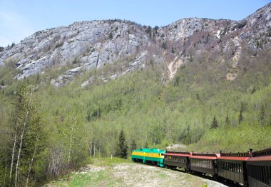 Beyaz Geçit 'ten geçen bir trenin bahar manzarası, Sınır Dağları' ndan geçen dağ 873 metre yüksekliğe ulaşır (Alaska).