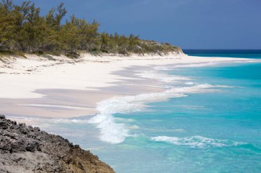 The scenic view of an empty sandy beach and turquoise color waves on Half Moon Cay uninhabited island (Bahamas).