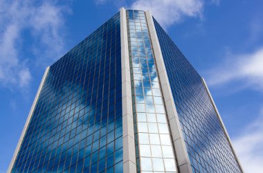 The abstract view of a glass covered blue color skyscraper with cloud reflections in Auckland downtown (New Zealand).