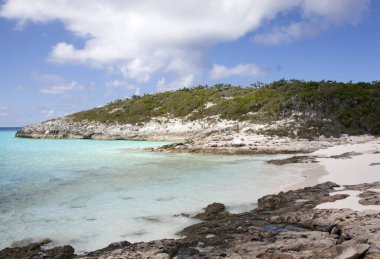 Half Moon Cay üzerinde kayalarla çevrili küçük kumlu bir sahil manzarası (Bahamalar)).