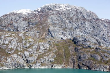 Buzul Körfezi Ulusal Parkı 'nda (Alaska) sarp bir kayalık kıyı ve küçük bir şelale manzarası).