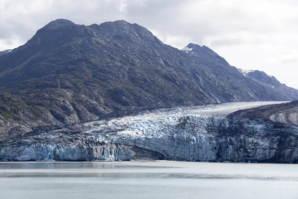 The Summer view of a melting glacier and a mountain in Glacier Bay national park (Alaska).