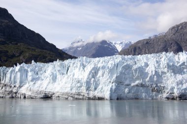 The scenic view on Summer of a large blue color glacier surrounded by mountains in Glacier Bay national park (Alaska).