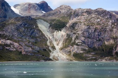 Yazın Buzul Körfezi Ulusal Parkı 'nda (Alaska) renkli kayalık kıyı ve buzlu suyun manzarası).