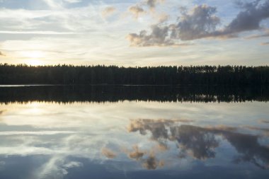 Baltis Gölü 'nün günbatımı manzarası sakin sular ve bulutlu gökyüzü yansımaları (Litvanya).