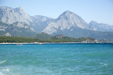 Akdeniz kıyısındaki Kemer tatil beldesi plajı ve arka plandaki yüksek dağların sabah manzarası (Türkiye).