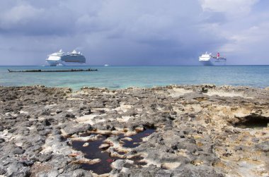 Büyük Cayman Adası 'ndaki Seven Mile Sahili' nin manzarası ve arkadaki yolcu gemilerinin üzerindeki karanlık gökyüzü (Cayman Adaları)).