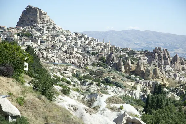 Bir vadideki Uchisar turizm kasabası ve tepenin üstünde bir mağara kalesi manzarası (Kapadokya, Türkiye).