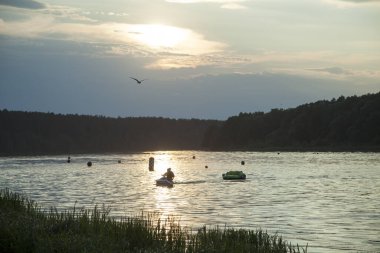 Birstonas tatil beldesi Neman Nehri 'nde su bisikleti süren turistlerin günbatımı manzarası (Litvanya).