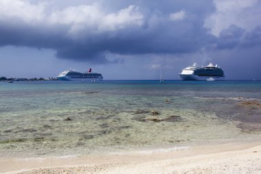 Büyük Cayman Adaları 'ndaki George Town yakınlarında yağmurlu gökyüzünün altında sürüklenen iki yolcu gemisinin manzarası).