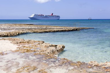 Büyük Cayman adasının manzarası ve arka planda sürüklenen bir yolcu gemisi (Cayman Adaları)). 