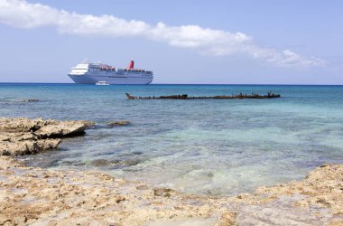 Grand Cayman Yedi Mil plajının manzarası ve arka planda bir yolcu gemisi olan batık bir gemi (Cayman Adaları)).
