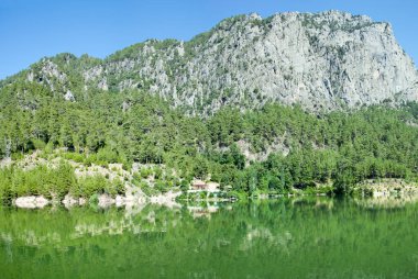Antalya ilinde (Türkiye) yüksek bir dağla yeşil renkli Karacaoren Gölü panoramik manzarası).