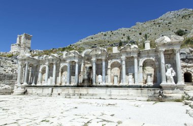 Çeşmenin güneşli manzarası, Sagalassos antik kenti olan Türkiye 'deki arkeoloji sahasında akan kaynak suyuyla harabe oluşturuyor..