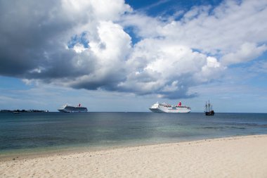 Yolcu gemilerinin manzarası ve Grand Cayman adası yakınlarında yağmurlu gökyüzünün altında sürüklenen bir korsan gemisinin kopyası.).