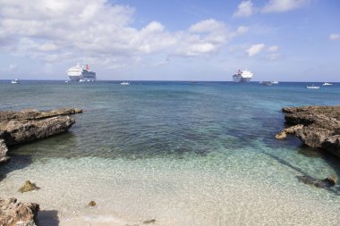 Seven Mile Beach 'in sabah manzarası ve arka planda birçok farklı tekneyle seyahat gemileri (Cayman Adaları)).