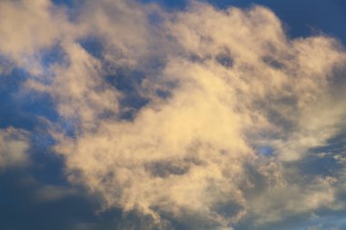 Gün batımında koyu mavi gökyüzünde turuncu bir bulutun manzarası.