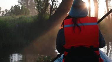 Meksika Xochimilco kanallarında kanoyla kürek çeken genç bir kadın.