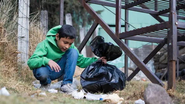 Latin çocuk parktaki çöp yığınını izlerken diz çöküyor.