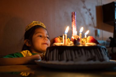 5 yaşındaki Meksikalı kız doğum gününü bir pastanın önünde kutluyor.