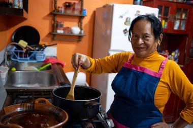 Önlük takıp yemek pişiren yaşlı Meksikalı kadın.