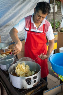 Meksikalı adam sokak yemeklerinde patates cipsi pişiriyor.