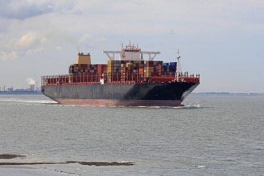 Büyük bir konteyner gemisi denizde seyrediyor.