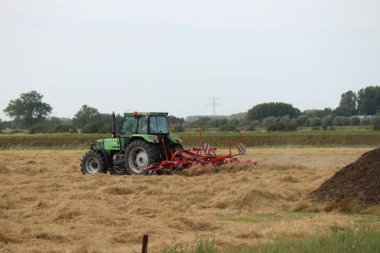 Yazın samanla tarlada gezen bir traktör.