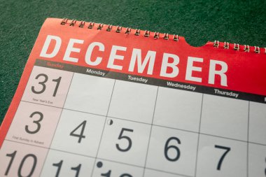 Calendar 2023, December, monthly planner. Day, month, year, date and activity organiser wall and desk planner. Red and white calendar with large letters and numbers on green background. Close up.
