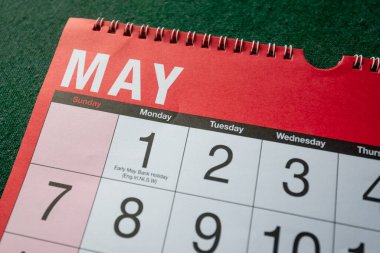 Calendar 2023, May, monthly planner. Day, month, year, date and activity organiser wall and desk planner. Red and white calendar with large letters and numbers on green background. Close up.