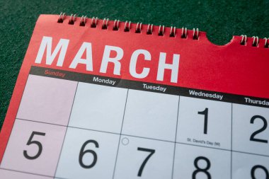 Calendar 2023, March, monthly planner. Day, month, year, date and activity organiser wall and desk planner. Red and white calendar with large letters and numbers on green background. Close up.