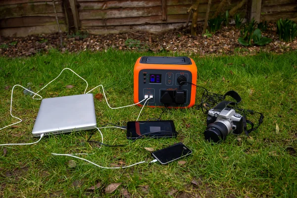Taşınabilir güneş enerjisi jeneratörü, dizüstü bilgisayar, tablet ve kamera elektronik cihazları bahçe çimlerinde şarj oluyor. Kablosuz şarj edilmiş lityum pil yedeği her yerde kullanılabilir..