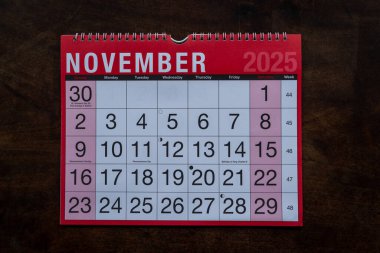 Takvim 2025, Kasım, aylık planlamacı. Gün, ay, yıl, tarih ve etkinlik düzenleyici duvar ve masa planlayıcısı. Ahşap zemin üzerinde büyük harfler ve rakamlar olan kırmızı ve beyaz takvim. 