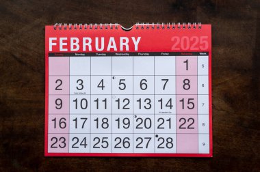 Takvim 2025, Şubat, aylık planlamacı. Gün, ay, yıl, tarih ve etkinlik düzenleyici duvar ve masa planlayıcısı. Ahşap zemin üzerinde büyük harfler ve rakamlar olan kırmızı ve beyaz takvim.