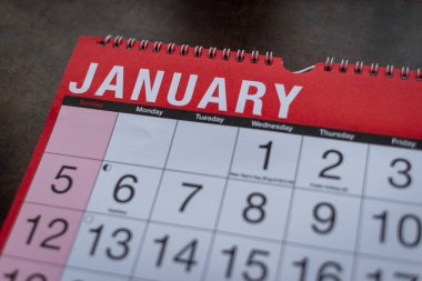 Takvim 2025, Ocak, aylık planlamacı. Gün, ay, yıl, tarih ve etkinlik düzenleyici duvar ve masa planlayıcısı kapanıyor. Ahşap zemin üzerinde büyük harfler ve rakamlar olan kırmızı ve beyaz takvim. 