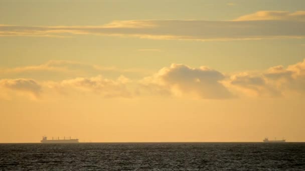 时间过去了大海中地平线上的谷物运输船和日落时黄色蓝天上快速移动的云彩的轮廓 自然背景 — 图库视频影像