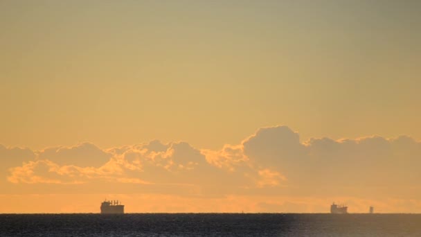 时间过去了大海中地平线上的谷物运输船和日落时黄色蓝天上快速移动的云彩的轮廓 自然背景 — 图库视频影像