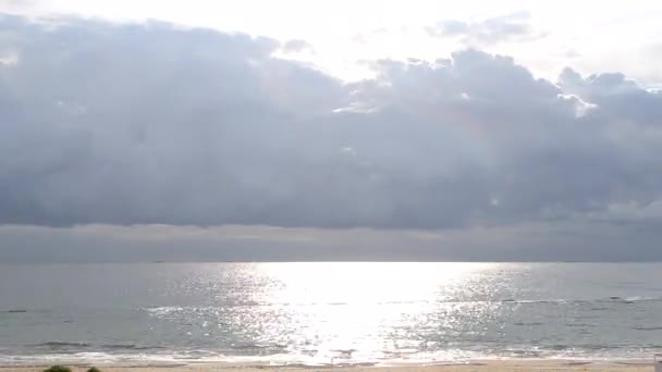 晴れた日には 海の表面上に雷雨の雨の大規模な雲のタイムラプス高速移動 明るく輝く太陽 海の波と砂浜の表面に日当たりの良いパス 自然背景 — ストック動画