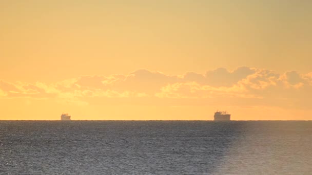 大海中地平线上的谷物运输船和日落时黄色蓝天上快速移动的云彩的轮廓 自然背景 — 图库视频影像