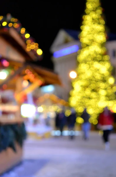 흐릿하다 크리스마스 나무는 노란색으로 장식되어 지붕에 등불로 거리를 사람들의 실루엣으로 — 스톡 사진